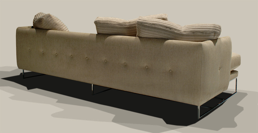 Paris Sofa featuring a long tufted light-colored upholstery and sleek metal legs