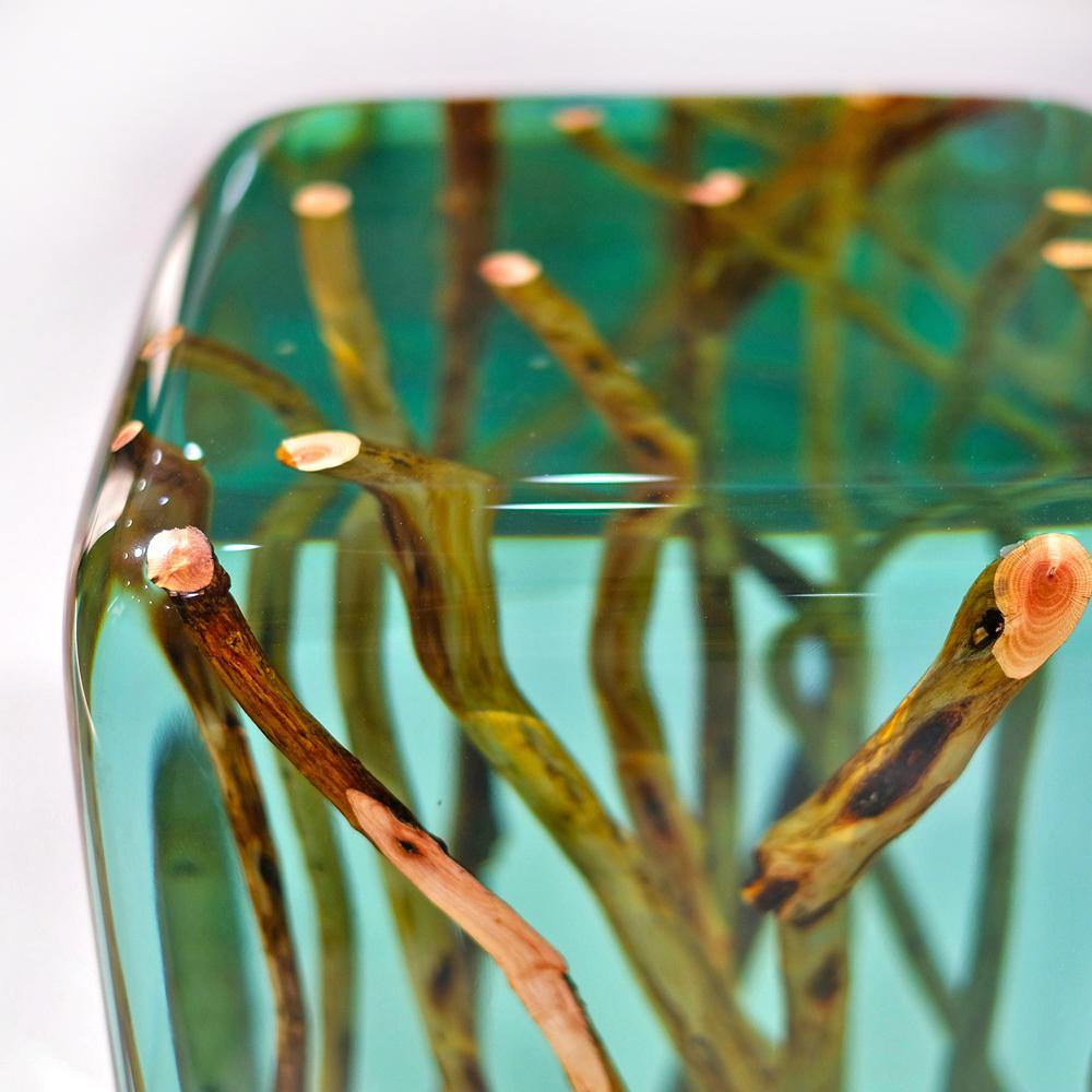 Green branches encased in transparent teal resin on a Green Branches End Table