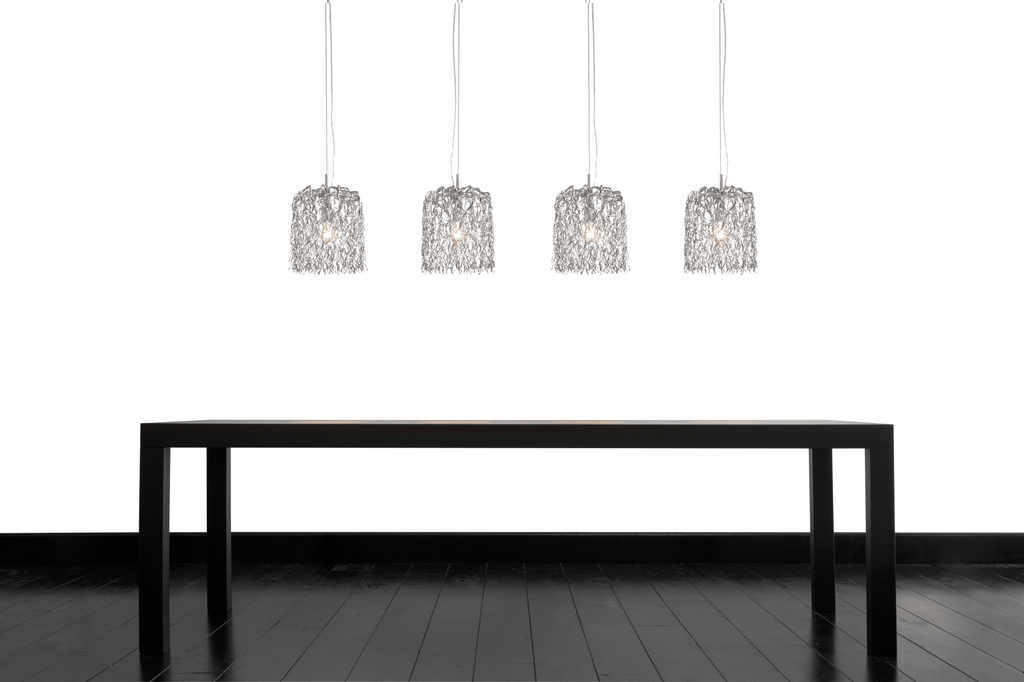 Hollywood Inline Hanging lamp over a long black dining table with silver pendant lights
