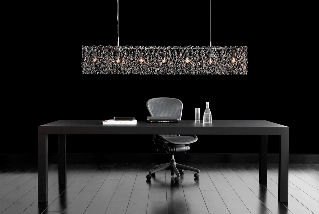 Hollywood Long Hanging lamp over a dark office desk with textured linear pendant light
