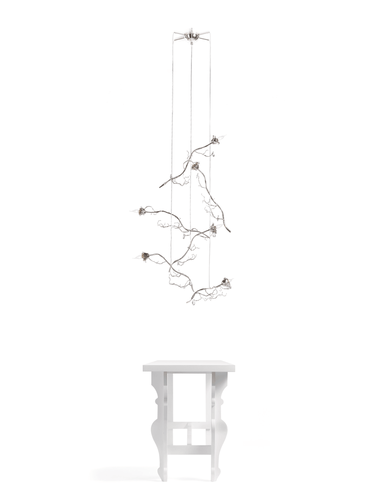 White metal chandelier with multiple branches over a white table for La Vie En Rosa single light rose