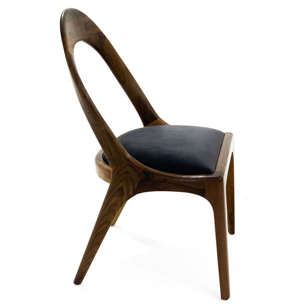Modern wooden Nyks Dining Chair with dark upholstered seat and distinctive curved backrest