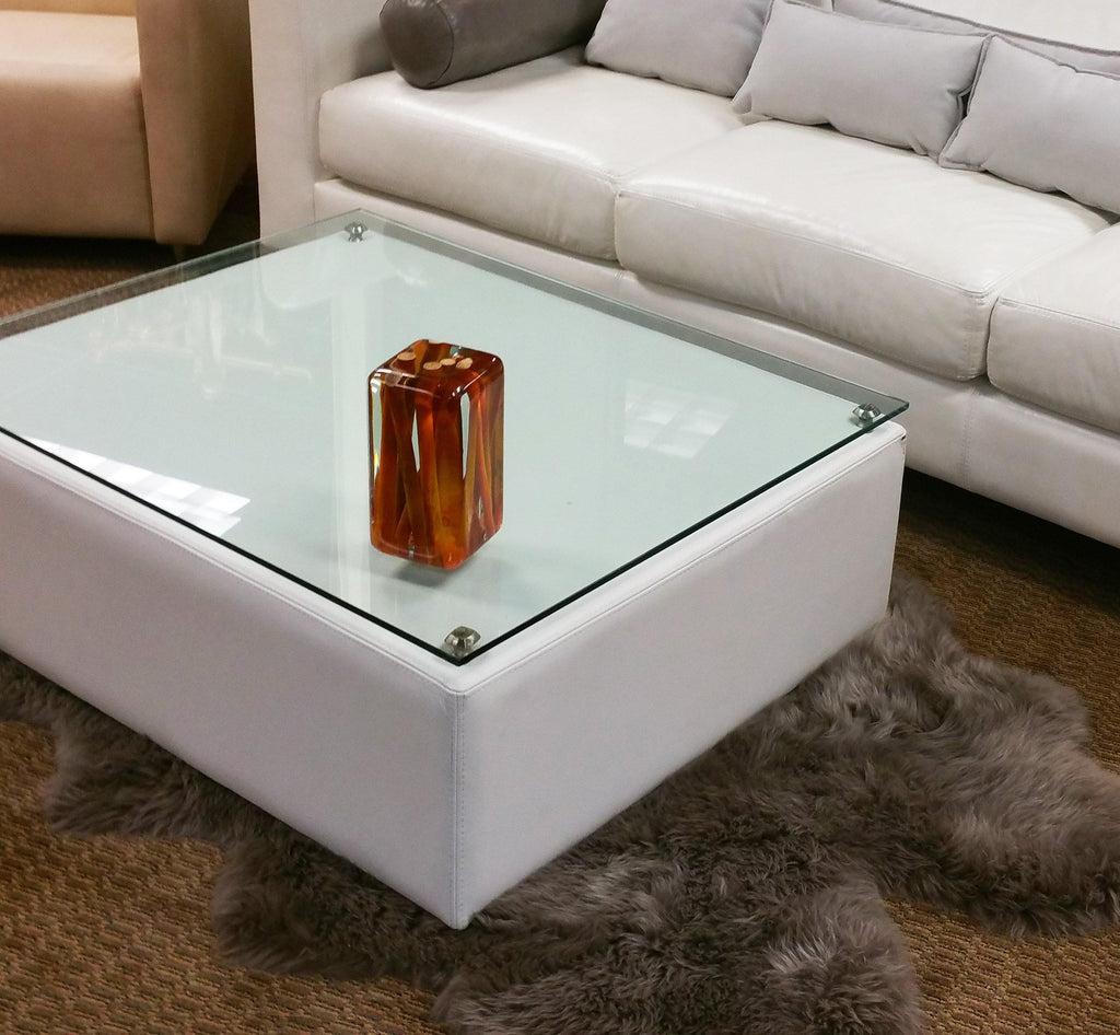 Orange Sticks Cube coffee table with glass top and reddish-brown decorative object